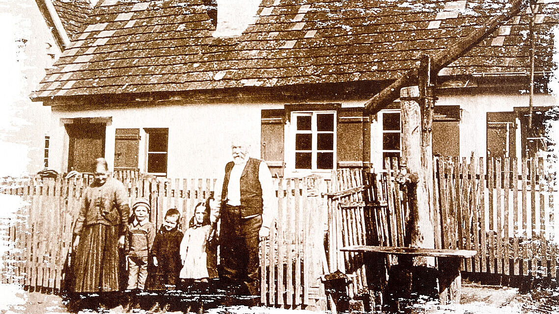 Familie steht vor einem Haus, daneben ein großer Brunnen Familie steht vor einem Haus, daneben ein großer Brunnen