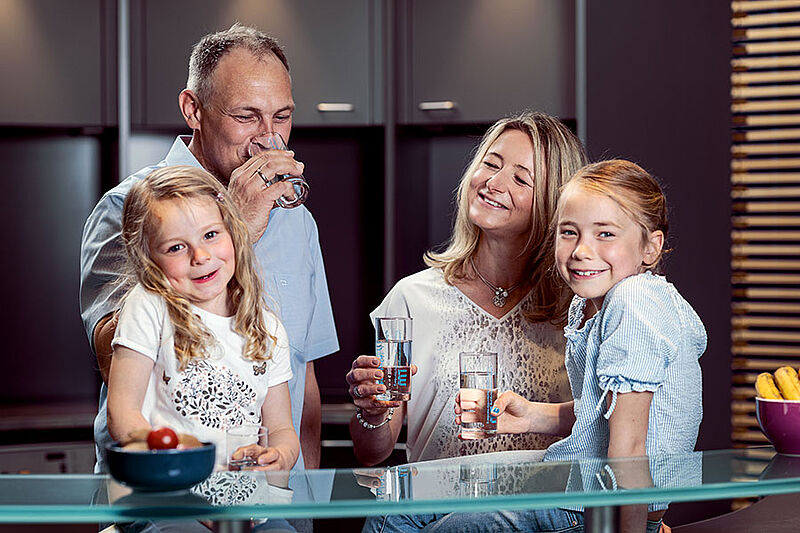Familie steht in der Küche und trinkt Wasser Familie steht in der Küche und trinkt Wasser