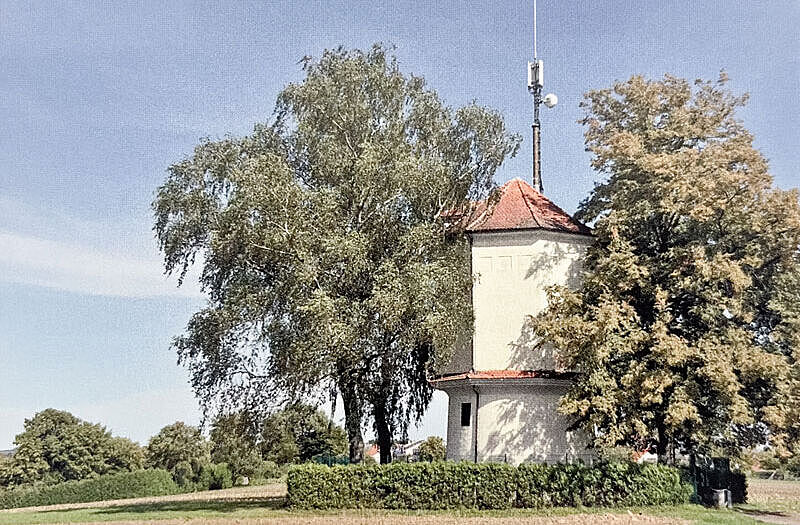 Ein Wasserturm umgeben von Böumen in einer grünen Landschaft Ein Wasserturm umgeben von Böumen in einer grünen Landschaft