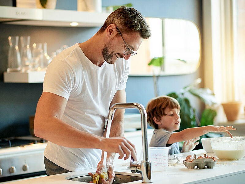 Mann steht mit Sohn in der Küche am Spülbecken Mann steht mit Sohn in der Küche am Spülbecken