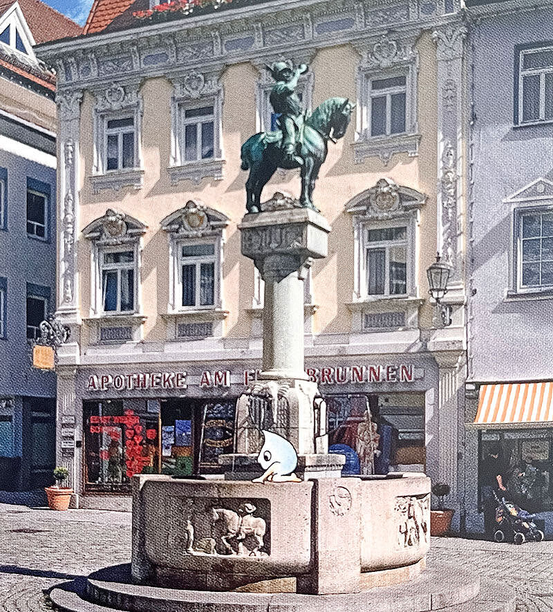 Brunnen mit einer Reiterstatue im Hintergrund und schönen alten verzierten Häusern Brunnen mit einer Reiterstatue im Hintergrund und schönen alten verzierten Häusern