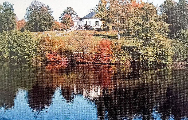 Ein Park mit Bäumen und Rasen, im Vordergrund ein See Ein Park mit Bäumen und Rasen, im Vordergrund ein See