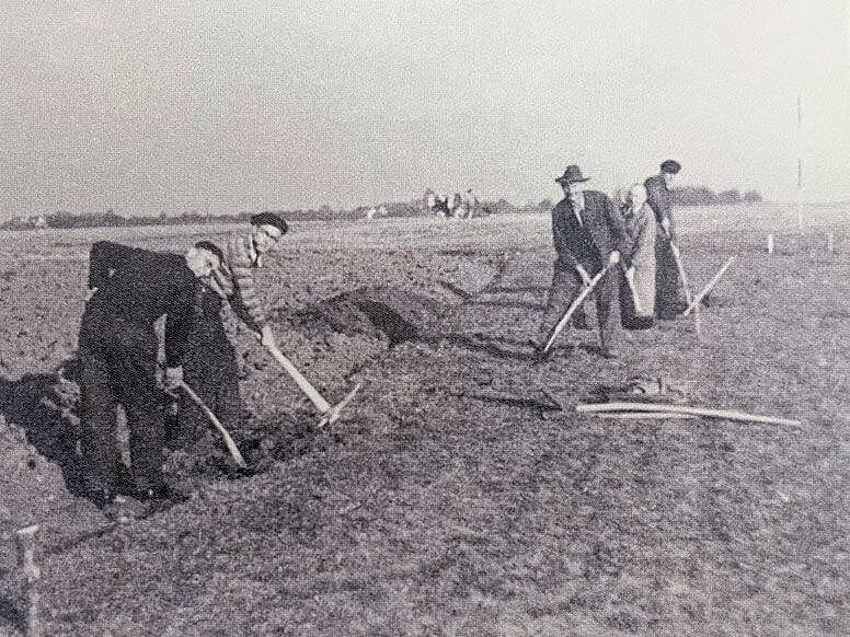 Einige Menschen auf dem Feld arbeiten an einem Graben Einige Menschen auf dem Feld arbeiten an einem Graben