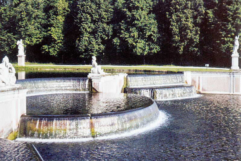 Stufenartiger Brunnen mit Figuren im Hintergrund Bäume