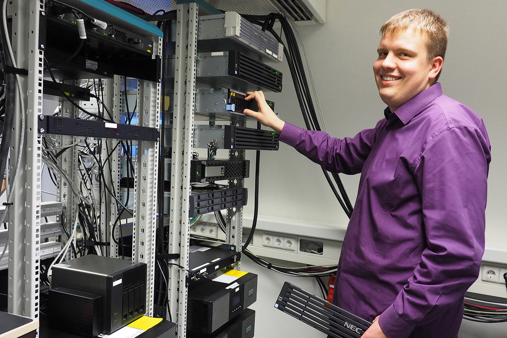 Junger Mann steht am Serverschrank Junger Mann steht am Serverschrank
