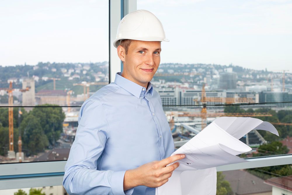 Mann mit Schutzhelm hält Pläne in der Hand Mann mit Schutzhelm hält Pläne in der Hand