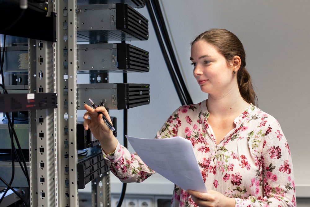Junge Frau macht sich Notizen am Serverschrank Junge Frau macht sich Notizen am Serverschrank
