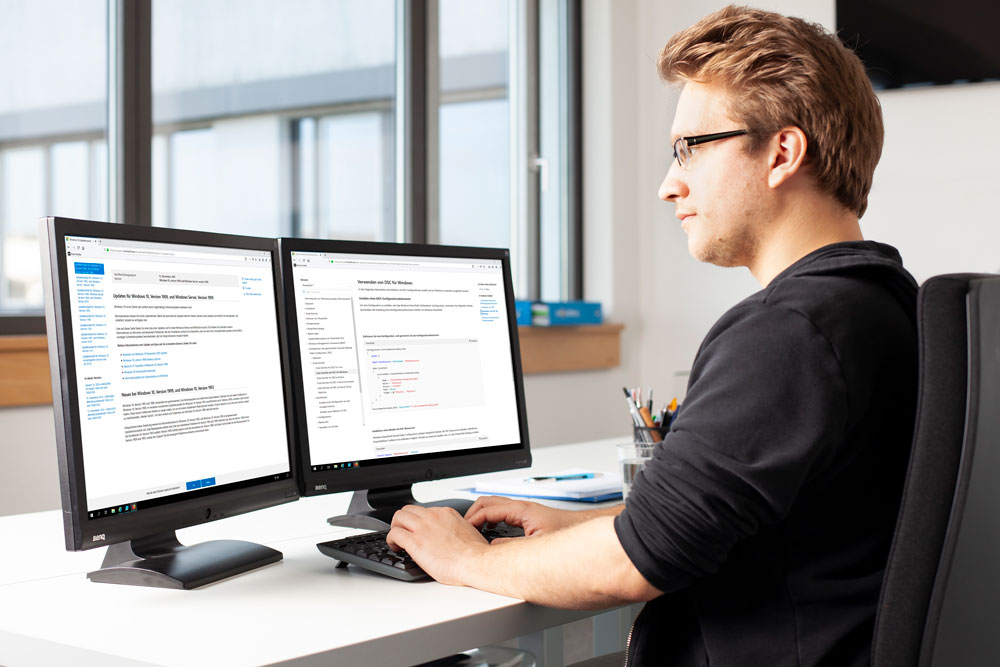 Junger Mann sitzt am Schreibtisch im Büro und arbeitet am Computer Junger Mann sitzt am Schreibtisch im Büro und arbeitet am Computer
