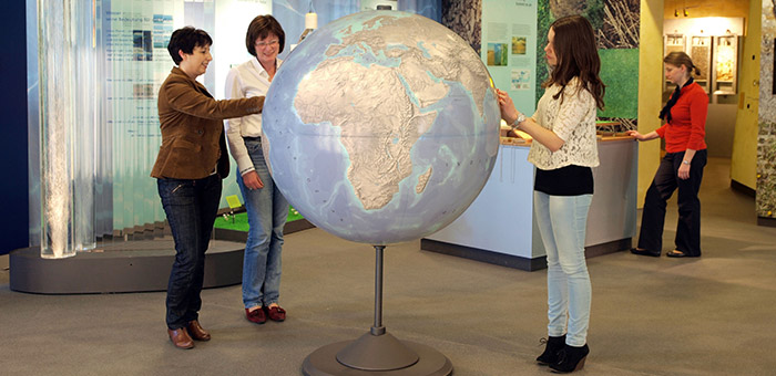 Besucher in der Ausstellung „Erlebniswelt Grundwasser“ an einem großen Globus