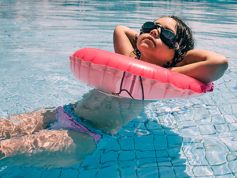 Mädchen liegt relaxt mit Schwimmreifen im Wasser Mädchen liegt relaxt mit Schwimmreifen im Wasser