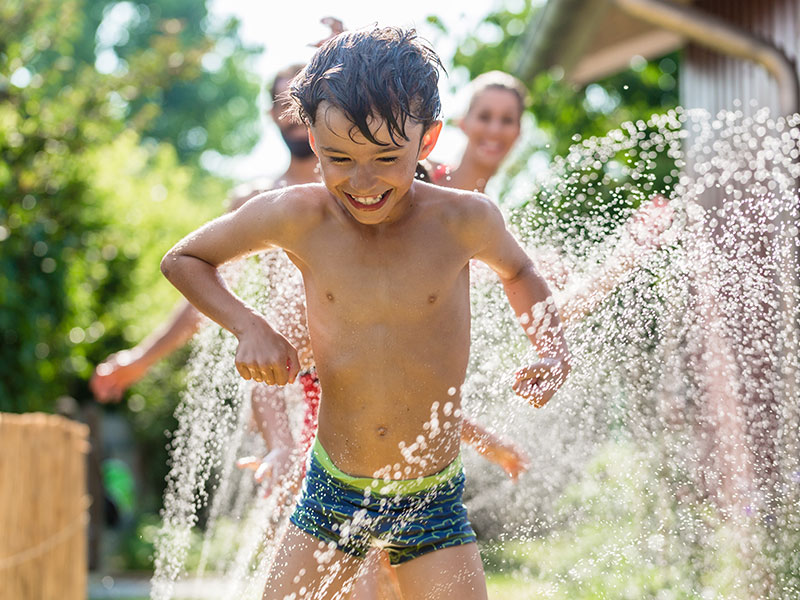 Kind im Garten spielt mit Wasser Kind im Garten spielt mit Wasser