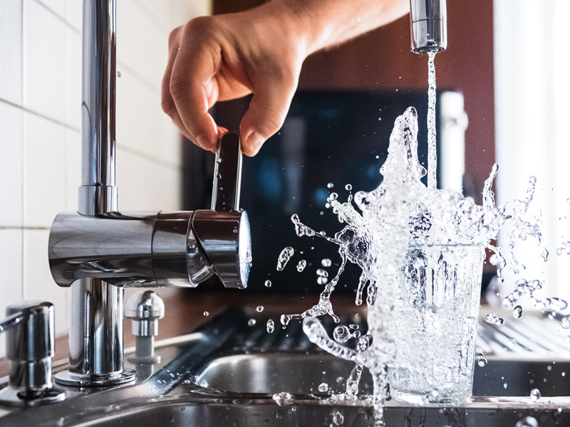 Glas Wasser wird mit Leitungswasser gefüllt